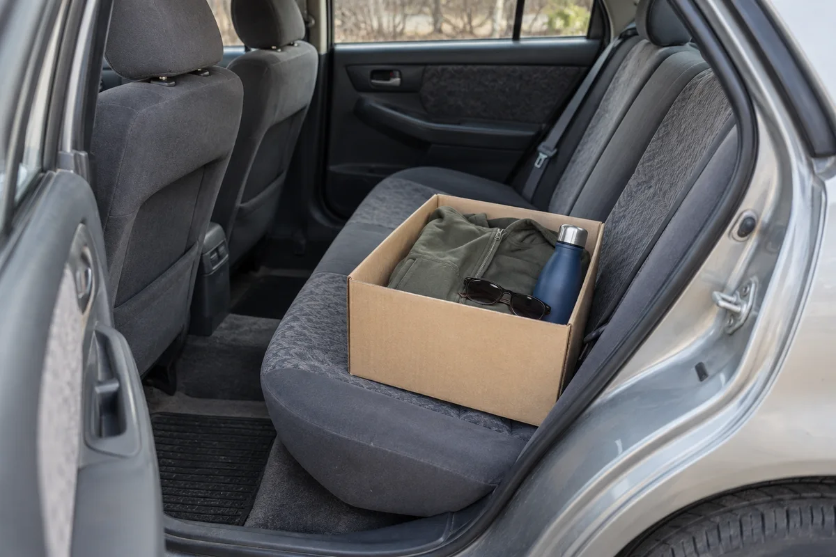 Personal belongings gathered in a box on a car seat.